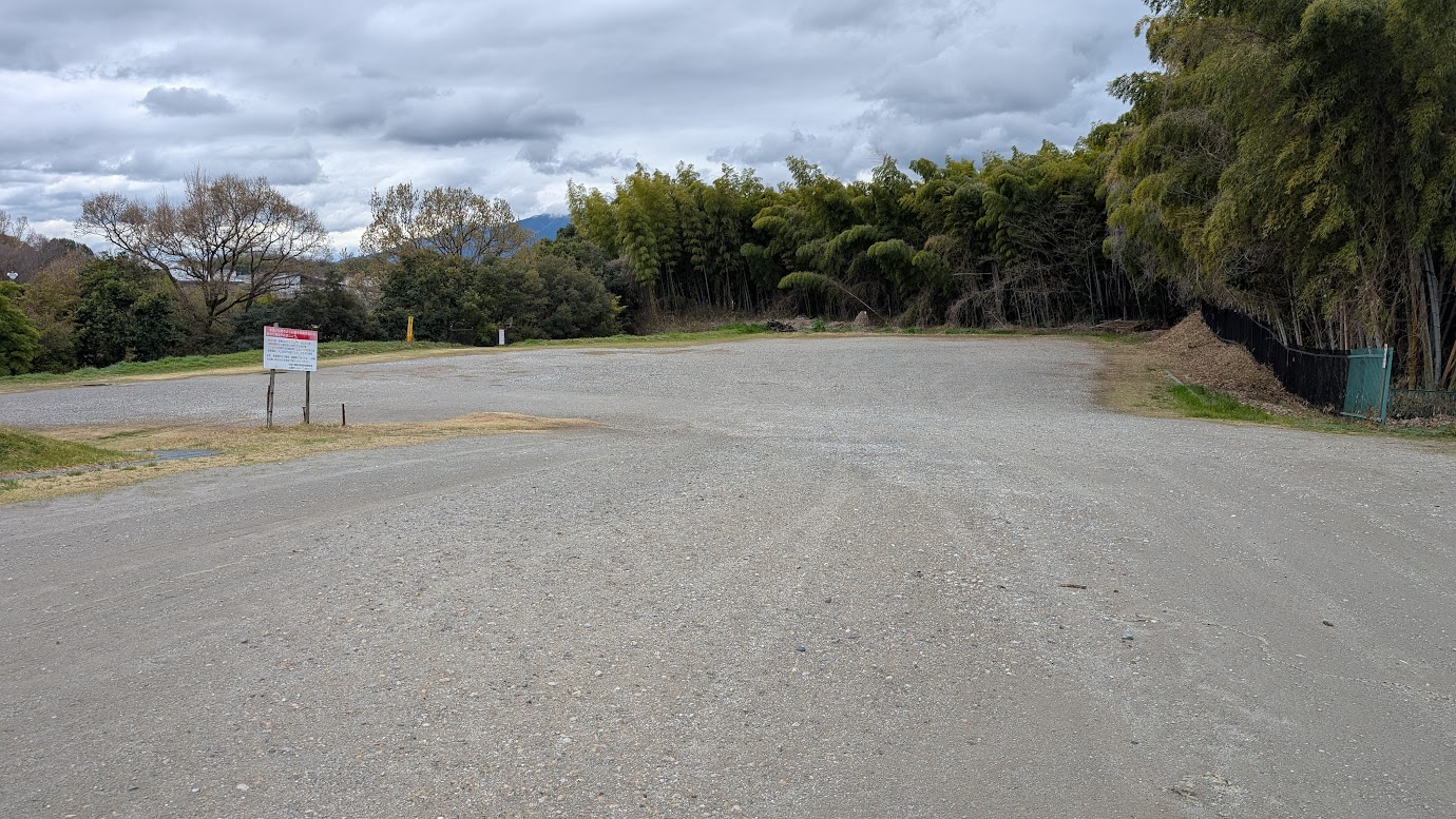 奈良県広陵町、竹取公園の最も奥にある広大な砂利敷きの駐車場。周囲を高い竹林と樹木に囲まれており、非常に広い空きスペースが広がっている。
