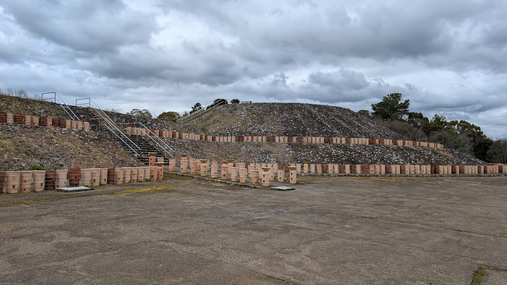 奈良県馬見丘陵公園にあるナガレ山古墳の全景。復元された前方後円墳の斜面には無数の円筒埴輪が並び、頂上へ続く階段と手すりが見える。空は曇り空。