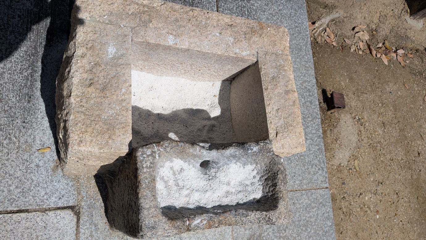 奈良県大和郡山市の大納言塚にある「お願いの砂箱」のフタが開けられた状態。木箱の中には白っぽい砂が満たされており、願いを込めて通された跡が残っている。