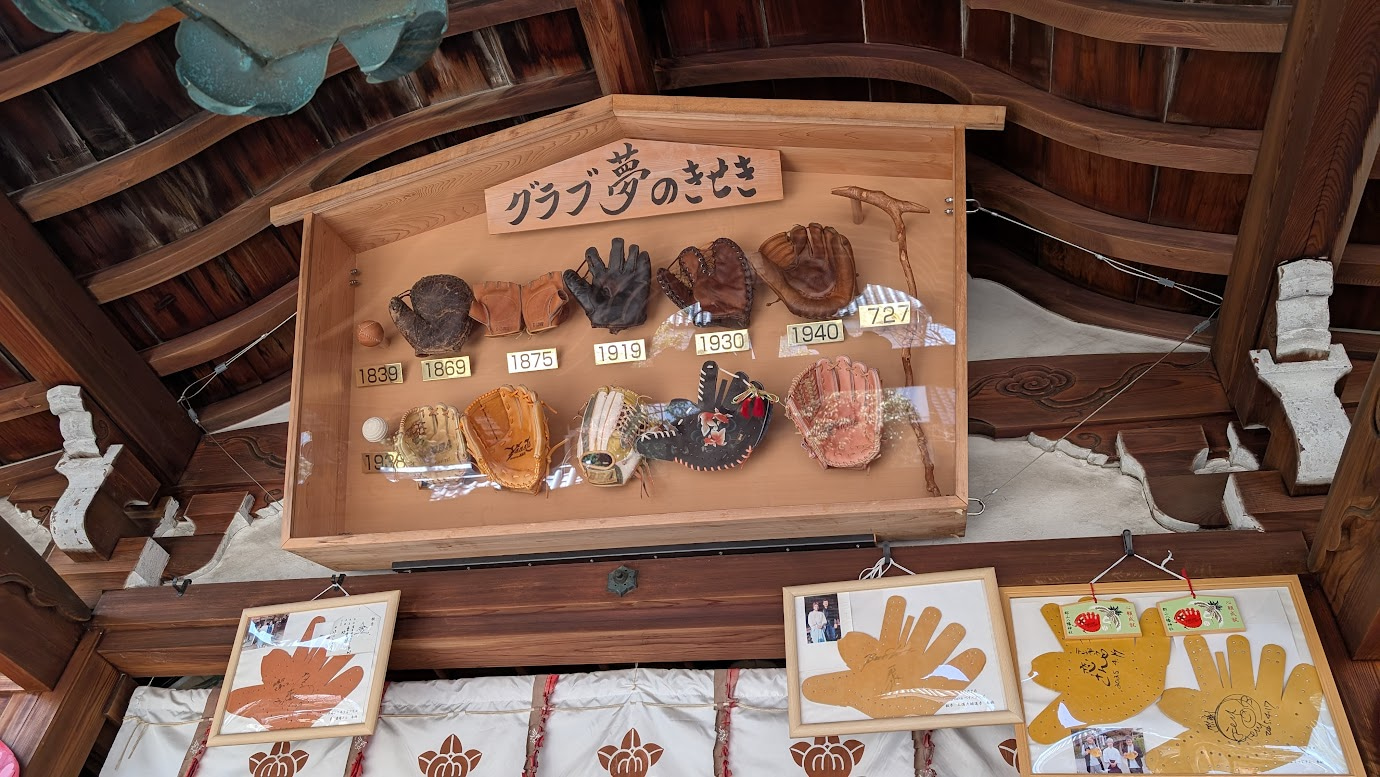 奈良県大和郡山市の郡山八幡宮、拝殿内に飾られた「グラブ夢のきせき」という展示ボード。1839年から現代までの野球グローブの進化が実物と年代プレートと共に紹介されている。