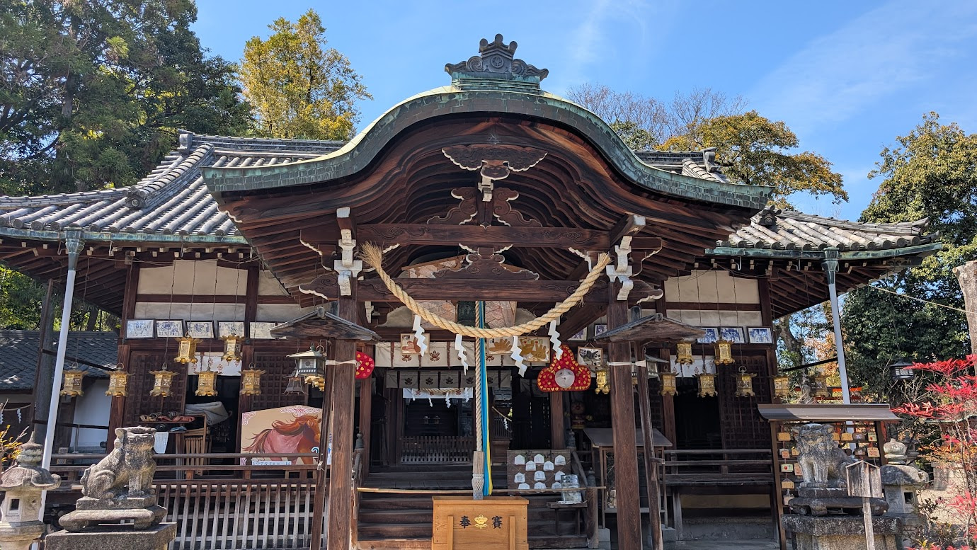 奈良県大和郡山市の郡山八幡宮の拝殿。重厚な瓦屋根と繊細な彫刻が施された木造建築で、手前には狛犬と大きな注連縄、お賽銭箱が設置されている。