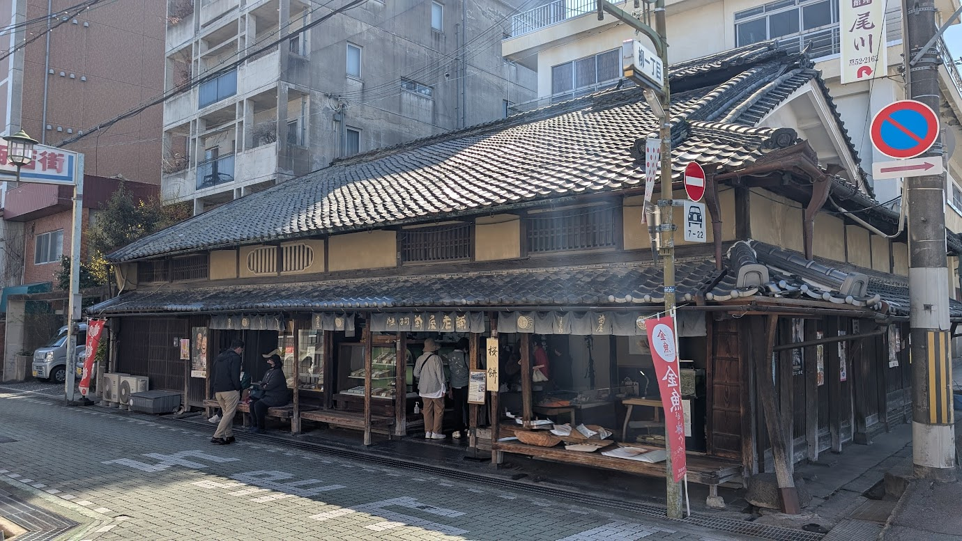 奈良県大和郡山市にある本家菊屋の外観。創業400年以上の歴史を感じさせる、重厚な木造建築の店構えで、金色の文字で書かれた看板が掲げられている。