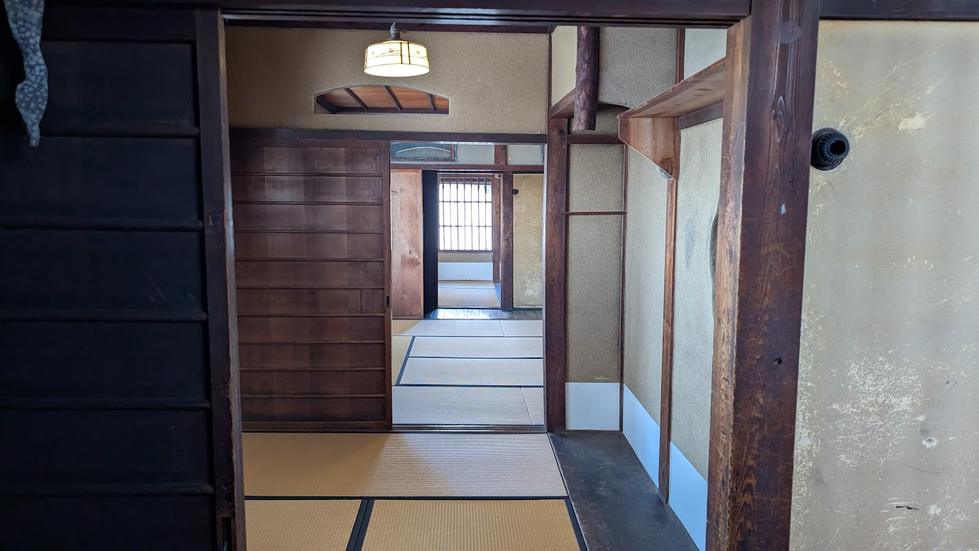 奈良県大和郡山市の町家物語館。旧遊郭時代の面影を残す畳敷きの座敷が奥へと続き、古い木造の建具や土間、特徴的な照明が歴史を感じさせる。