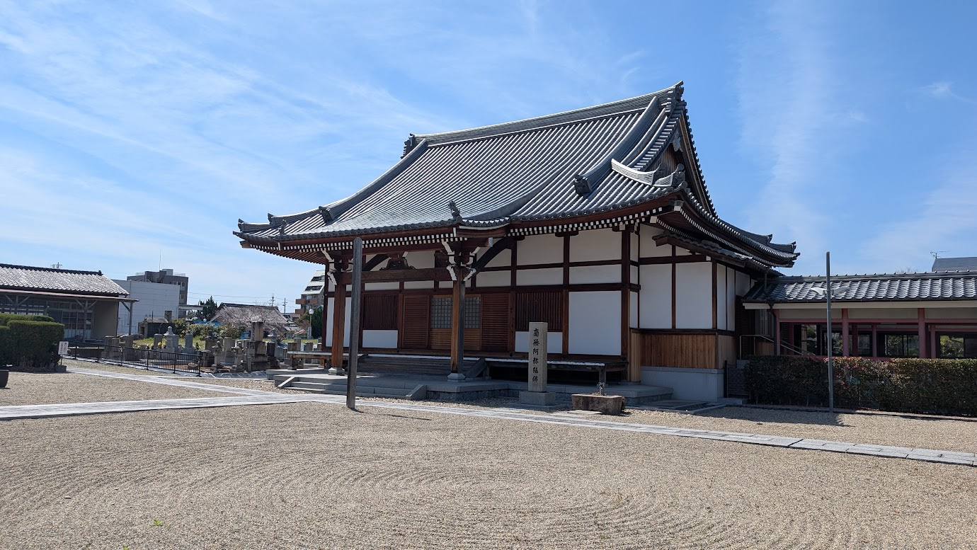 奈良県大和郡山市にある洞泉寺の本堂。重厚な瓦屋根の木造建築で、手前には砂紋が描かれた美しい枯山水の庭が広がっている。空は晴天。