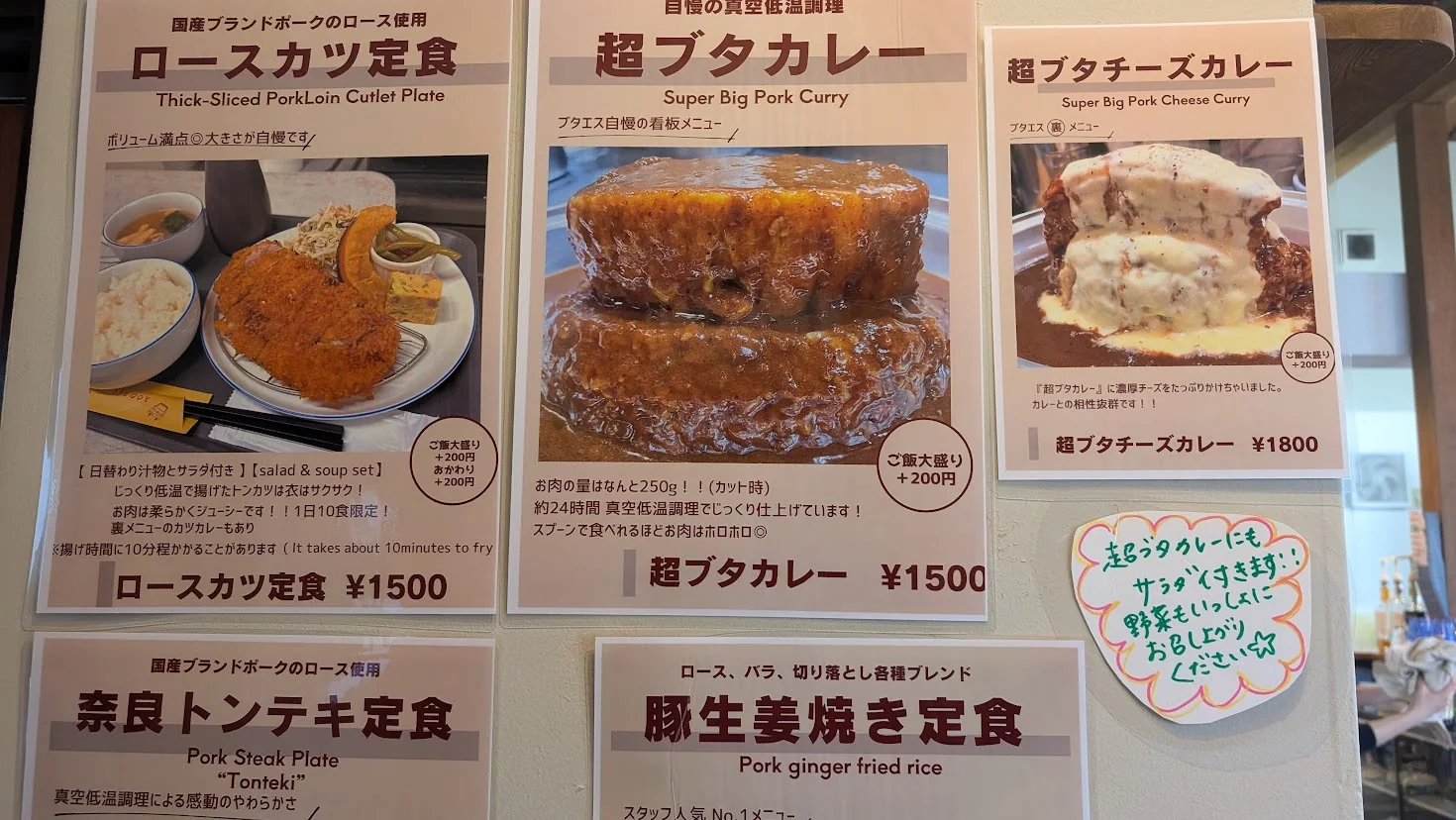 名物の「超ブタカレー」「超ブタチーズカレー」と「ロースカツ定食」の写真付きメニュー表。お肉の量が250gであることなどが解説されている。