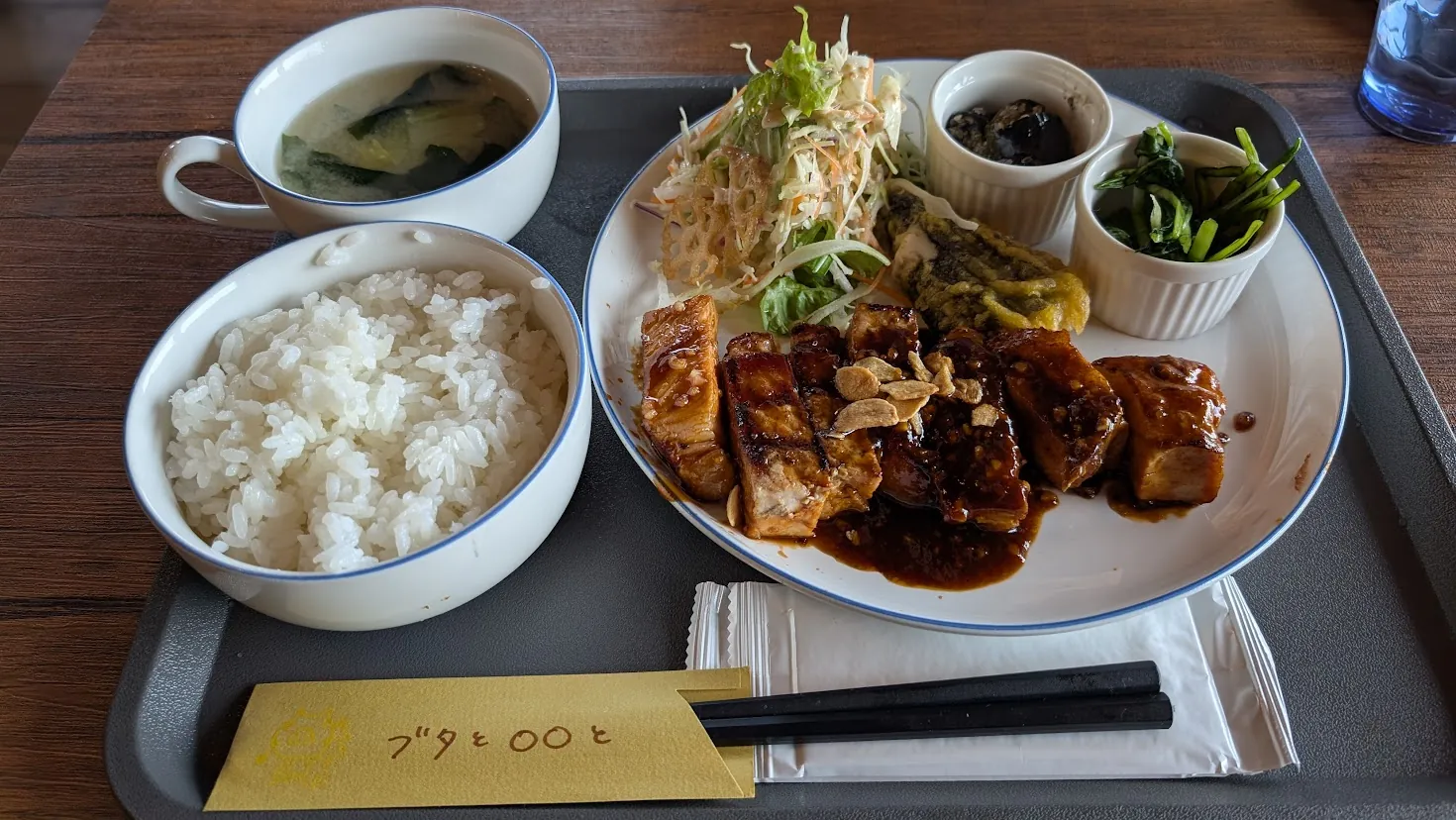 明日香村の「工場内食堂 ぶたと〇〇と。」で提供される「奈良トンテキ定食」の全体写真。ガーリックチップが乗った分厚いトンテキを中心に、山盛りのご飯、お味噌汁、彩り豊かなサラダ、2種類の小鉢がお盆に並べられたボリューム満点の定食風景。