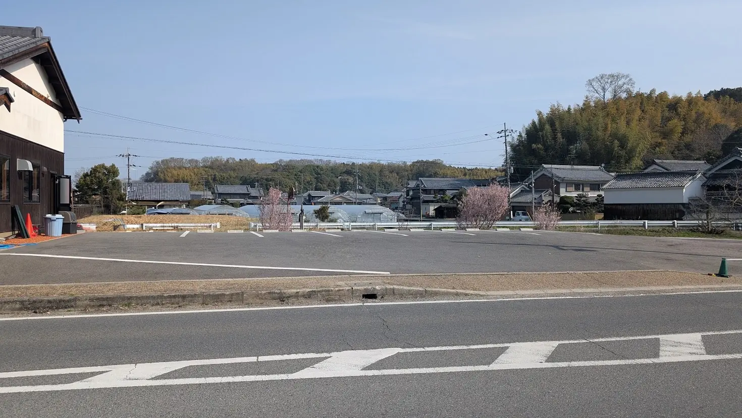 明日香村の「工場内食堂 ぶたと〇〇と。」の店舗すぐ横にある広々とした専用駐車場の風景。綺麗に舗装された平坦な敷地に、白線で区切られた停めやすい駐車スペースが広がっている。