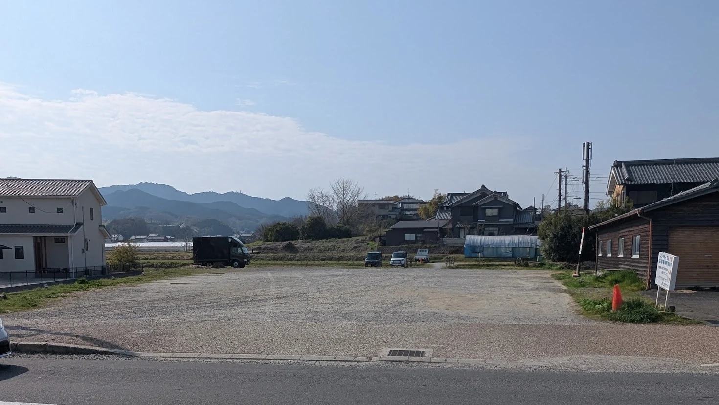 「工場内食堂 ぶたと〇〇と。」の店舗目の前にある「あすか夢販売所 第二駐車場」の風景。未舗装の砂利敷きだが非常に広々としており、車が停めやすい広大なスペースが広がっている。