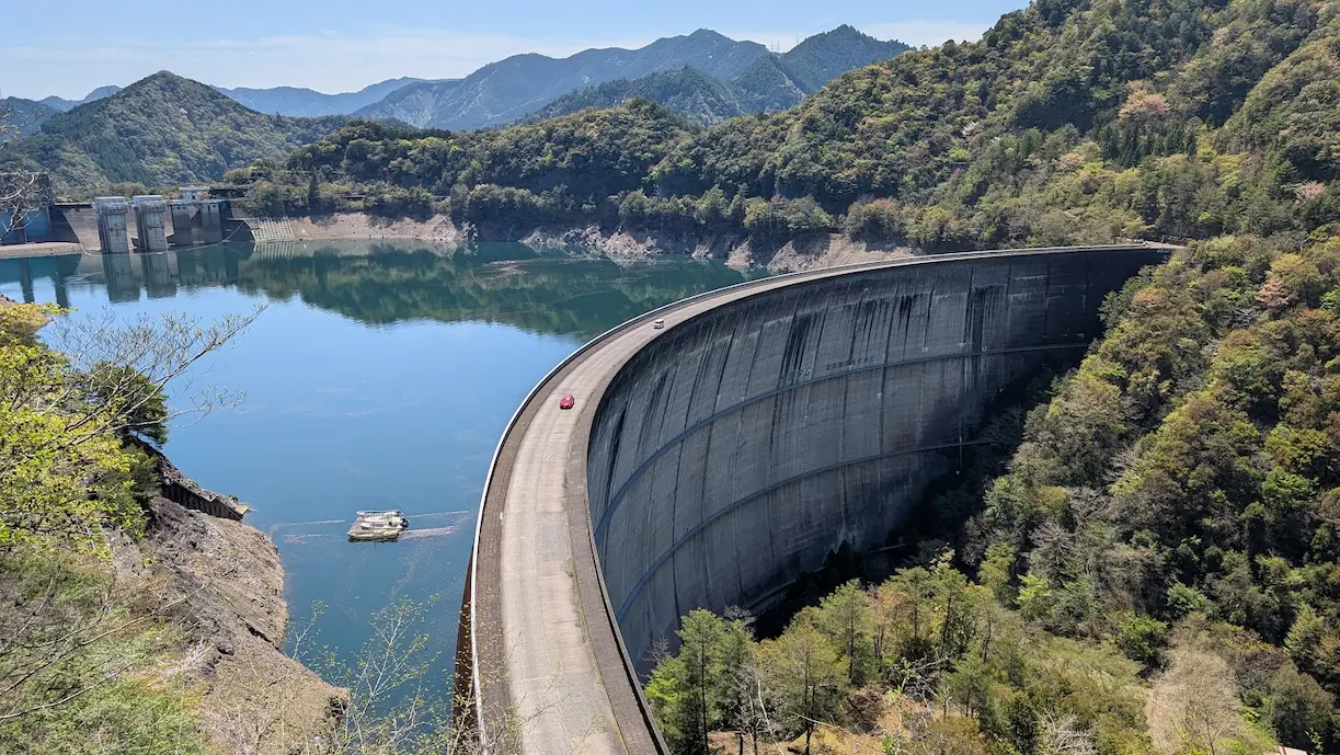 高台から見下ろした、巨大なアーチを描く池原ダムの堤体と静かなダム湖の全景