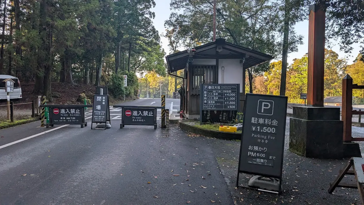 春日大社本殿前駐車場の入口ゲートと、料金（乗用車1,500円）および閉場時間が記載された案内看板