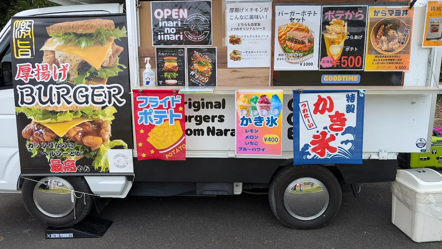 キッチンカーの側面に貼られたメニュー。厚揚げバーガー単品やポテトセット（1000円）、かき氷（400円）、から揚げポテト（500円）などの価格と写真が詳しく載っている