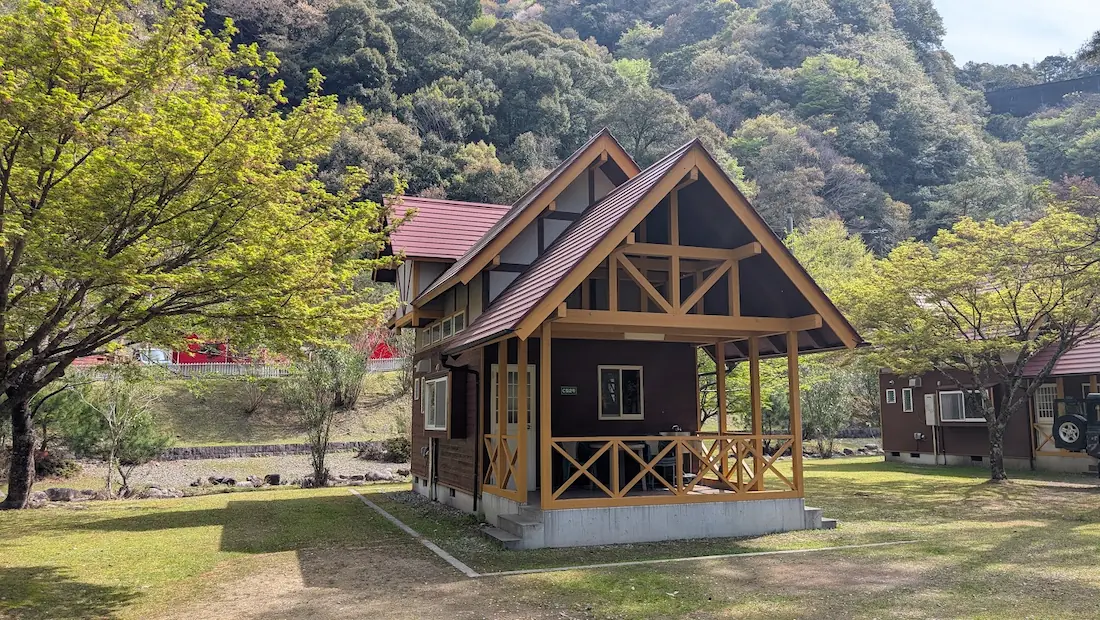 下北山村きなりの郷にある、池原ダムを背にした木造のC型コテージ外観