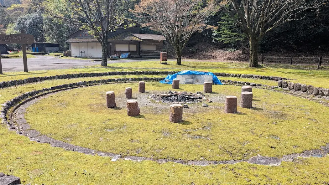 きなりの郷キャンプサイト内にある、丸太の椅子が並ぶ石造りのファイアー場(キャンプファイヤー場)