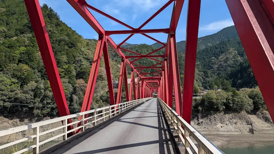 下北山村の林泉禅寺へと続く、深い山々に囲まれた鮮やかな赤い鉄橋の風景
