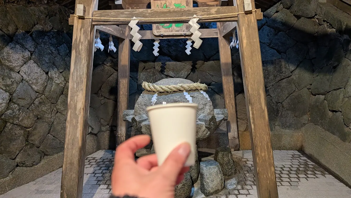 狭井神社の霊泉にて、備え付けの紙コップに注がれた清らかな御神水（薬水）をいただく様子。