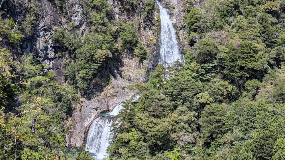 奈良県下北山村にある「不動七重の滝」の全景。幾段にも分かれて流れ落ちる巨大な滝と、周囲を囲む深い緑の断崖絶壁が織りなす壮大な風景。
