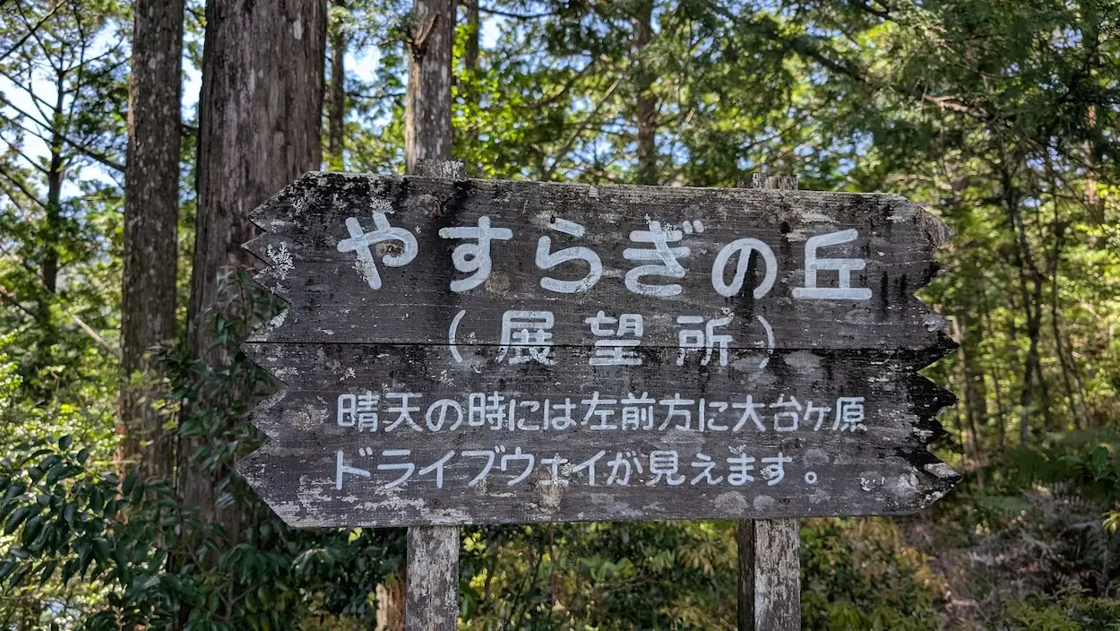 奈良県下北山村、明神池周遊歩道内の「やすらぎの丘(展望所)」案内看板。晴天時には大台ヶ原ドライブウェイが見える旨が記された木製看板。