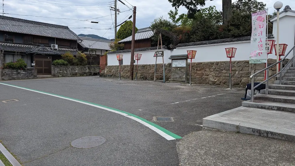 奈良・石光寺の山門すぐ横にある第1駐車場。アスファルト舗装されており、右側にはお寺へ続く階段と牡丹祭りののぼりが立っている広々とした駐車スペースの風景