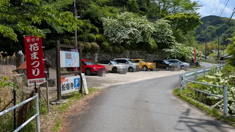 船宿寺の参道沿いにある、数台分の駐車スペースと境内案内図。赤い「花まつり」の幟が立っている風景