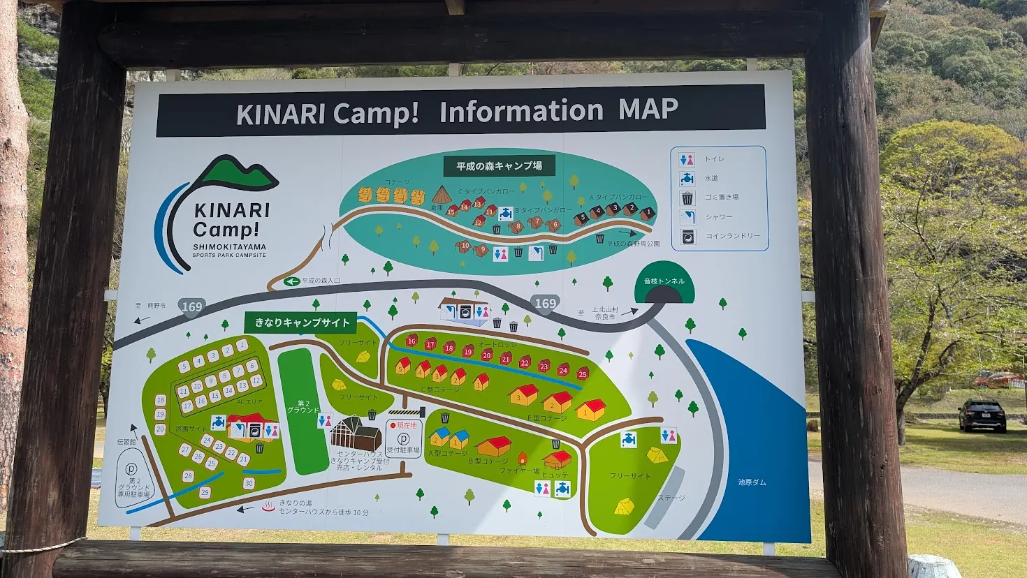 「KINARI Camp! Information MAP」と書かれた看板。きなりキャンプサイト、平成の森キャンプ場、コテージ、受付、池原ダムなどの位置関係がイラストで詳しく描かれている案内図