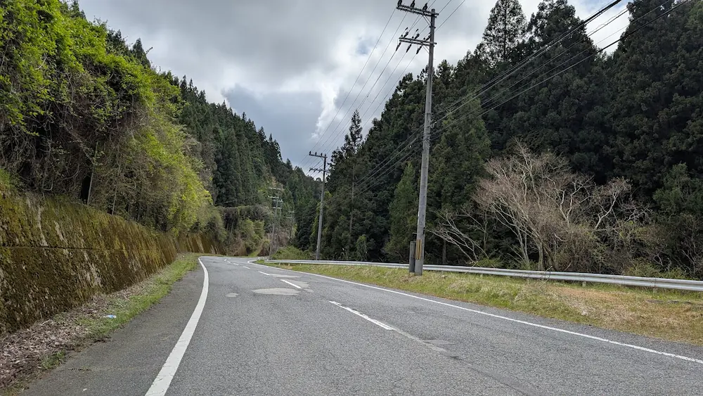 宇陀・弁財天へと続く、周囲を深い緑の山々に囲まれた、綺麗に舗装された片側一車線の道路。空は少し曇っている