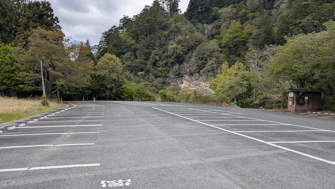 奈良・室生寺の広大な有料駐車場。アスファルトで舗装され、白線で一画ずつ綺麗に区画分けされている。背景には山々の新緑が見える