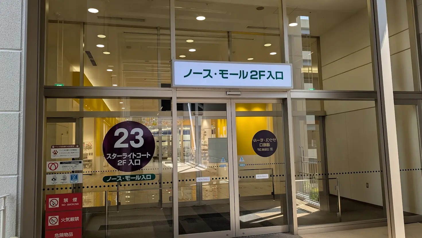 イオンモール橿原の駐車場から「2F ノースモール入口（23番）」へ向かう案内板と、その入り口の様子。