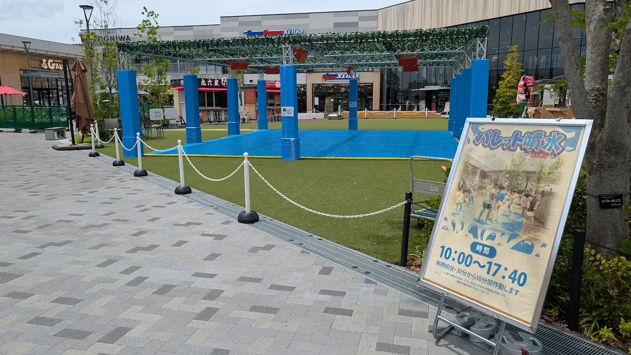 イオンモール橿原ウエストビレッジにある「パレット噴水」の全景。人工芝エリアと作動時間を示した案内看板。