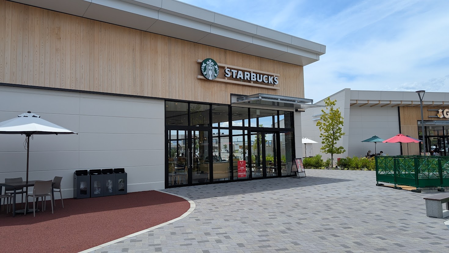 イオンモール橿原ウエストビレッジにあるスターバックスの店舗全景。木目調の外壁と大きなガラス窓が特徴的な外観。