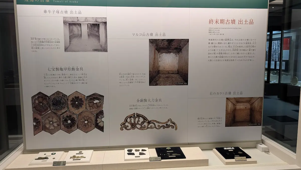 飛鳥資料館の「終末期古墳 出土品」展示。牽牛子塚古墳、マルコ山古墳、岩のカラト古墳の石室写真と、七宝製亀甲形飾金具などの装飾品が解説パネルとともに展示されている。