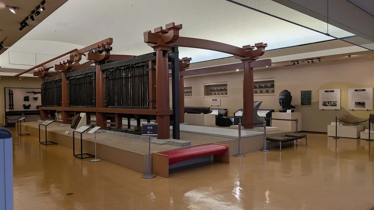 飛鳥資料館に展示されている山田寺東回廊の復元展示。1300年前の本物の木材(黒ずんだ柱や連子窓)を、赤い補強フレームで支える形で当時のスケールそのままに再現している。