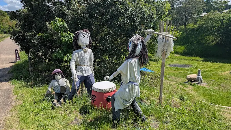 キトラ古墳近くの散策路に設置された、太鼓をたたく案山子の家族人形。飛鳥ののどかな風景の中にある手作りオブジェ。