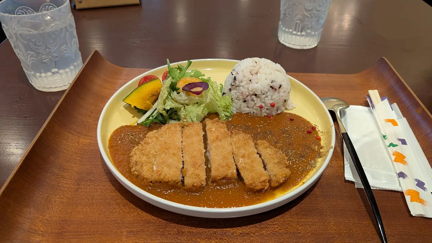 明日香村のランチスポット「カリオン」にて、黄色いプレートに盛り付けられた厚切りカツカレーと彩り豊かなサラダの全体写真