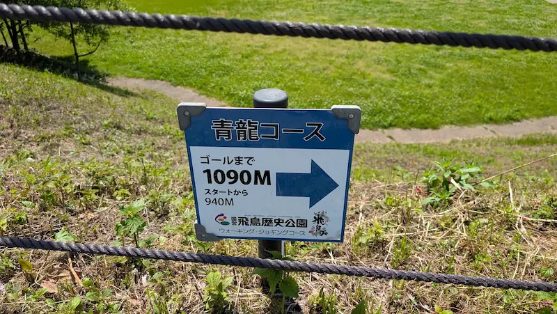 国営飛鳥歴史公園のウォーキング・ジョギングコース「青龍コース」の案内看板。ゴールまで残り1090mを示す矢印が表示されている。