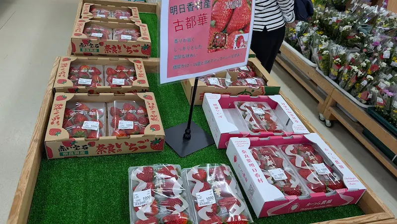 奈良県明日香村の直売所に並ぶ高級いちご「古都華(ことか)」。箱詰めされた鮮やかな赤い古都華が陳列され、品種の紹介ポップが添えられている様子。