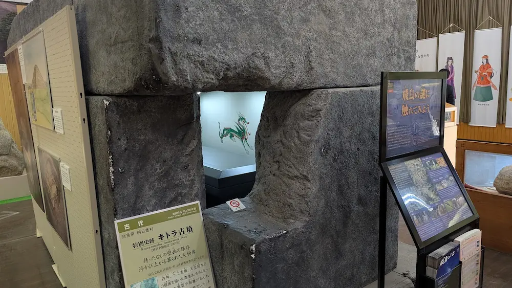 明日香村埋蔵文化財展示室に展示されているキトラ古墳の石室の実物大レプリカ。大きな石を組んだ隙間から内部が見えるようになっており、奥の白い壁には緑色の「青龍」の壁画がリアルに再現されている。
