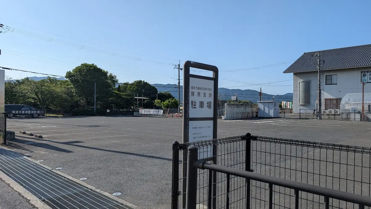 藤原宮跡の駐車場入口に設置された案内看板。アスファルト舗装された広々とした駐車スペースの様子。