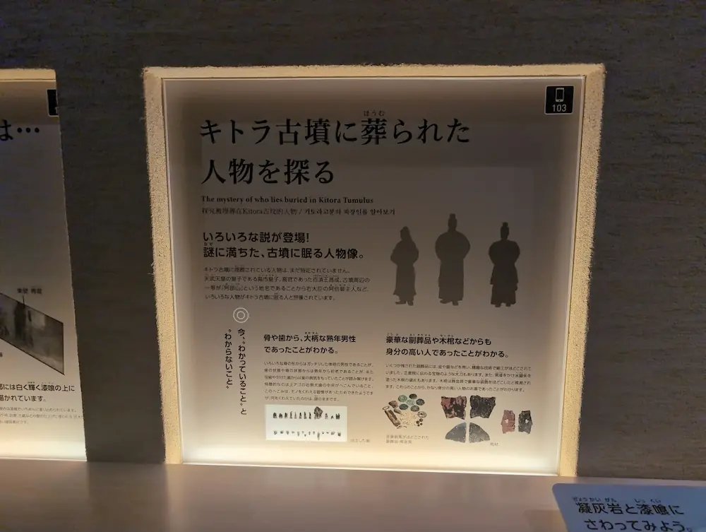 キトラ古墳に誰が埋葬されているかを探る展示パネル。「阿部御主人」などの説や、出土した歯、豪華な副葬品についての説明がある。