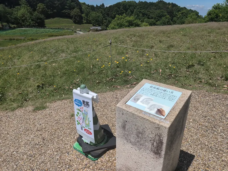 キトラ古墳の乾拓体験ができる石柱と説明看板。古墳の石室壁画を紙に写し取る方法が書かれている。