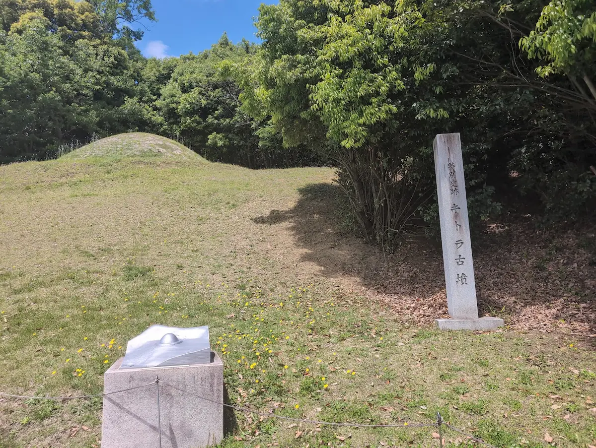 キトラ古墳の石碑と、その横にある古墳内部の石室模型。緑豊かな丘の麓に設置されている。