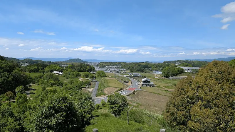 キトラ古墳の展望台から望む明日香村の風景。緑豊かな田園地帯と歴史的な集落、遠くの山々が見渡せるパノラマビュー。