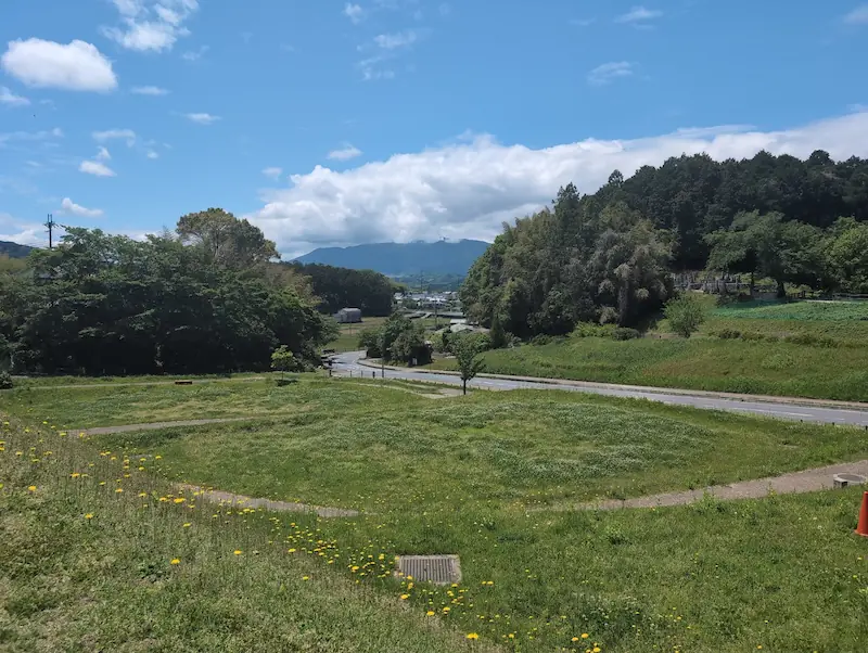 キトラ古墳周辺の整備された遊歩道。緑豊かな広場と、その先に広がる山々の景色。