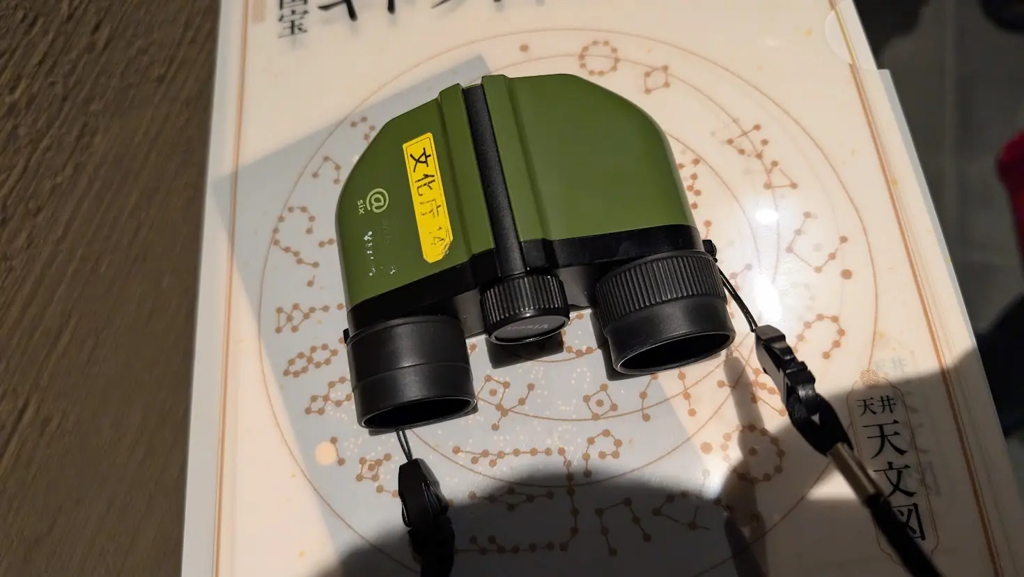 キトラ古墳壁画公開会場にて、観覧用に貸し出される緑色のVixen製単眼鏡。背景には天文図の解説資料が写っている。