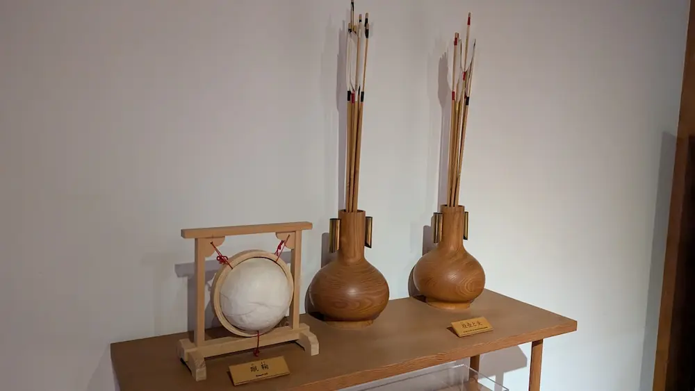 万葉文化館の展示品。左側に木製の台に置かれた白い蹴鞠、右側に矢が刺さった二つの投壺（とうこ）が木製のテーブルに並んでいる。