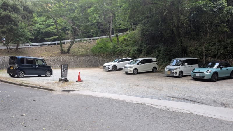 松尾寺の山門近くにある駐車場。未舗装の広場に数台の車が駐車されており、周囲を木々に囲まれている。