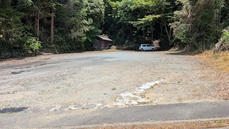 松尾寺にある未舗装の広い駐車場。周囲を森に囲まれており、駐車スペースに余裕がある。