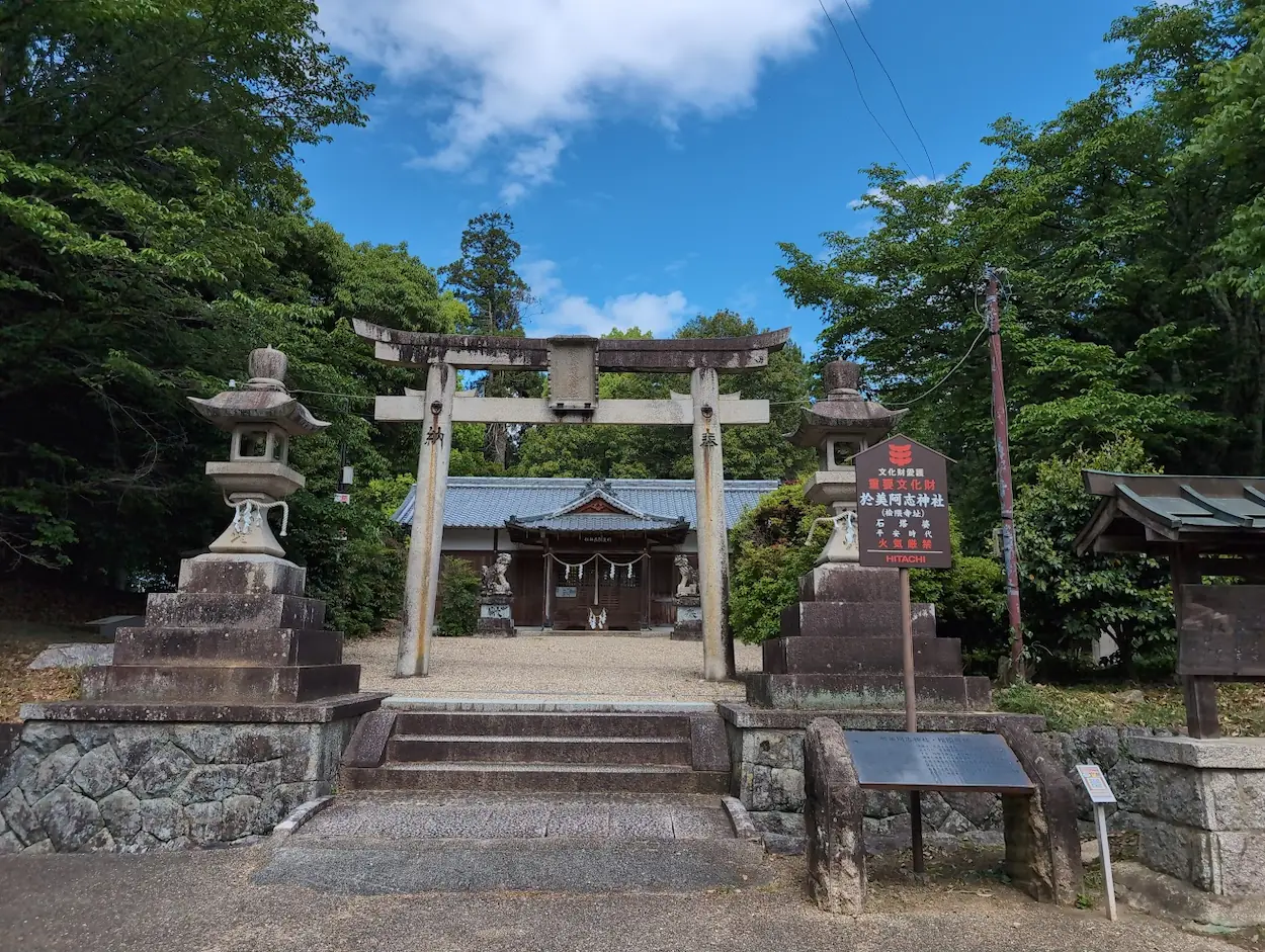 於美阿志神社の境内入口。石造りの鳥居と、その奥に見える重厚な本殿、左右の石灯籠が配置された静寂な空間。