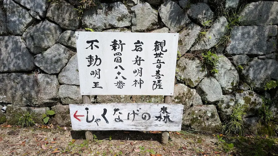 船宿寺の石垣の前に立てられた、「しゃくなげの森」への左矢印と、観世音菩薩・岩舟明神・不動明王などが祀られていることを示す案内板