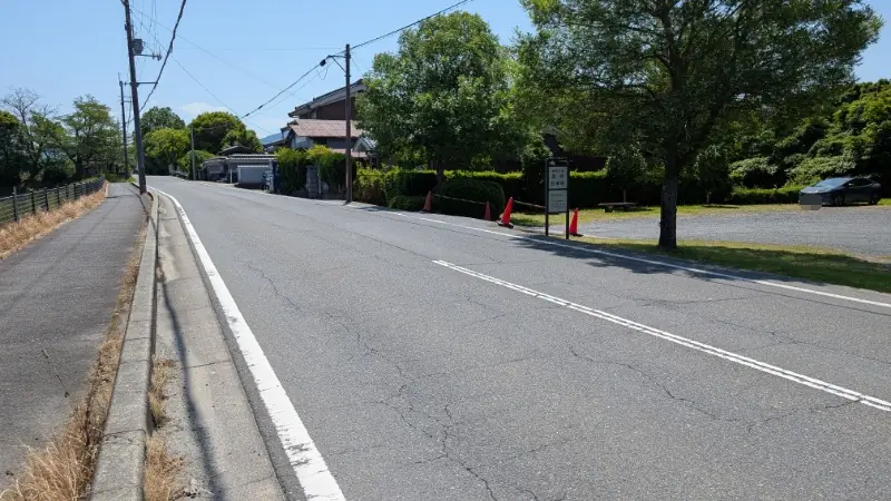 藤原宮跡周辺にある、未舗装で砂利敷きの臨時駐車場1への入り口。道路沿いに看板が設置されている様子。