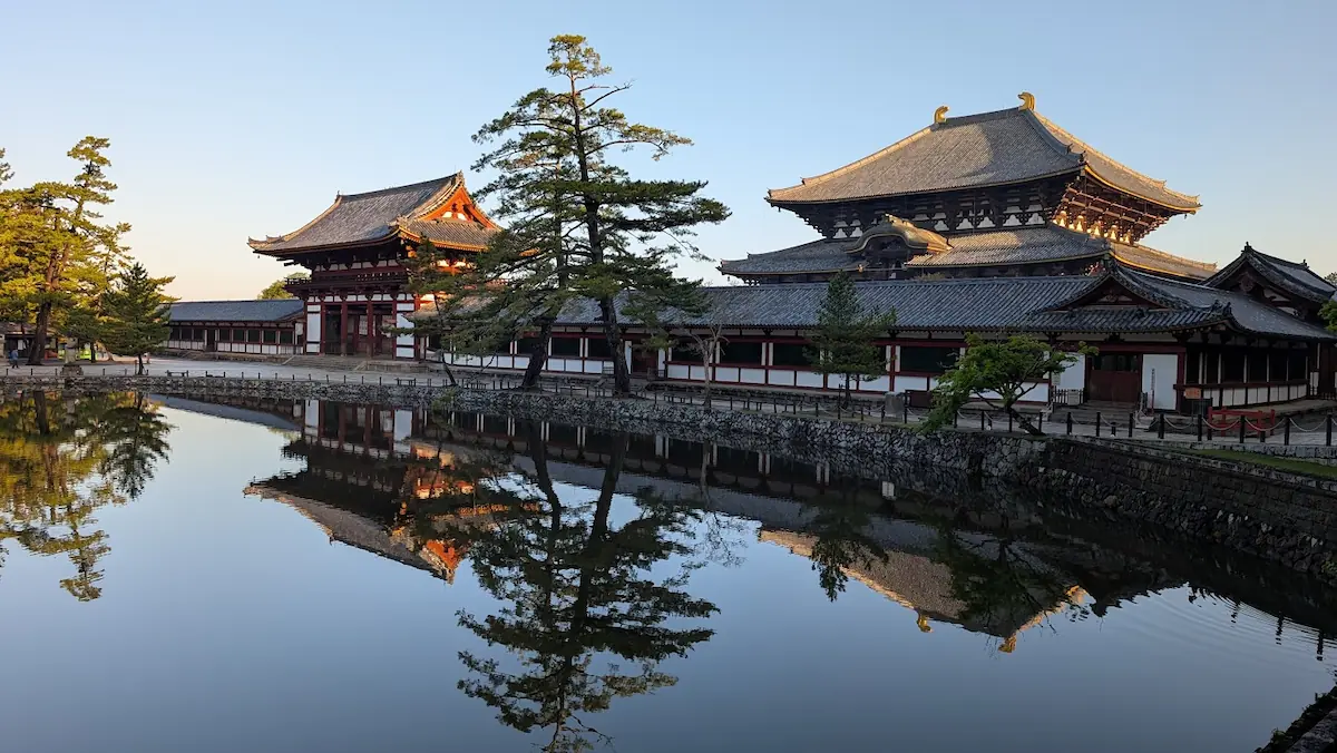 東大寺鏡池の側面からのリフレクション。朝陽を浴びて輝く中門と大仏殿の重厚な建築が、青い水面に反射している様子